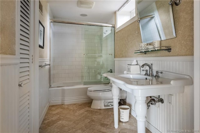 full bathroom with toilet, shower / bath combination with glass door, and sink