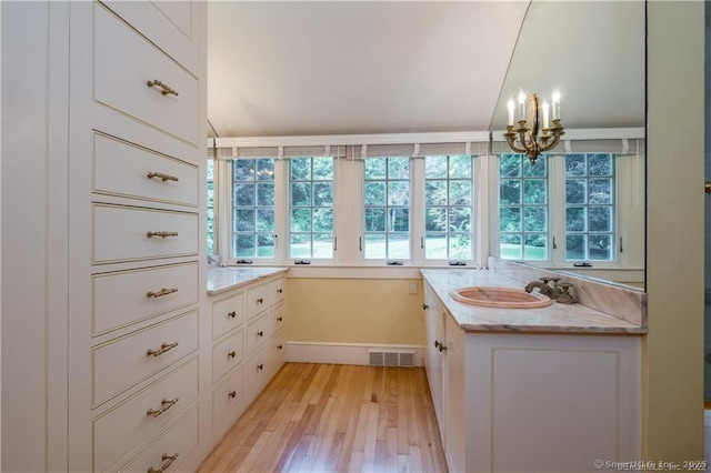 bathroom featuring a chandelier, a wealth of natural light, vanity, and wood-type flooring