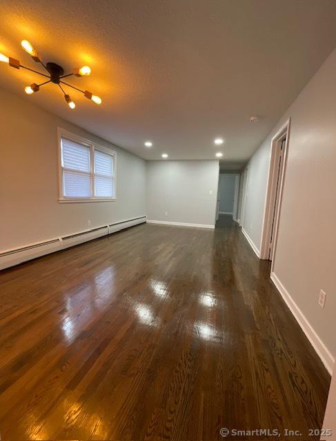 spare room with ceiling fan, dark hardwood / wood-style flooring, and a baseboard radiator