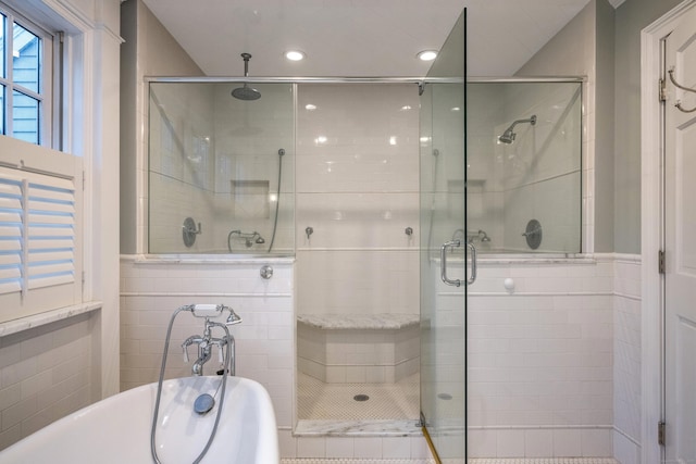 bathroom with tile walls and shower with separate bathtub