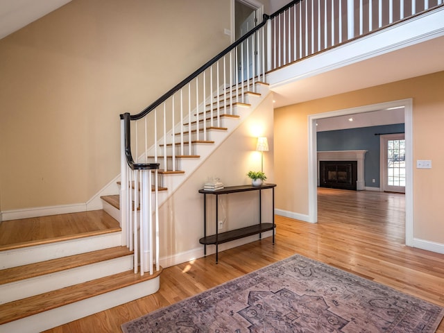 stairs featuring a towering ceiling and wood-type flooring