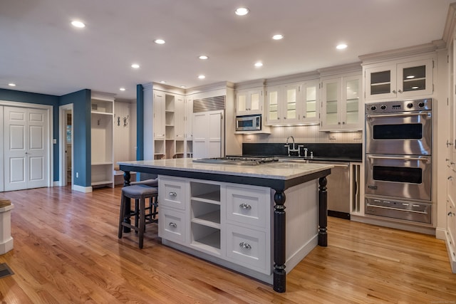 kitchen with built in appliances, a kitchen island, white cabinetry, and a kitchen bar