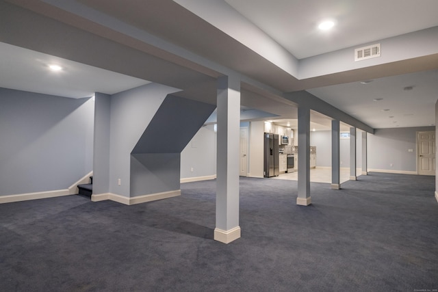 basement featuring stainless steel fridge and dark carpet