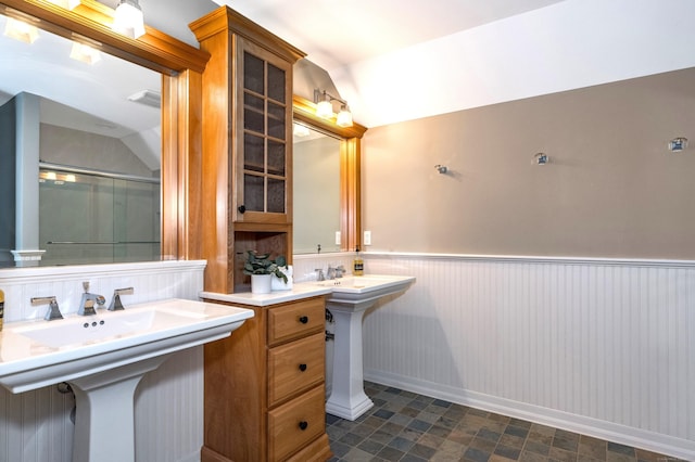 bathroom featuring lofted ceiling and dual sinks