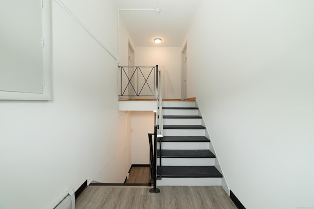 staircase featuring a baseboard radiator and wood-type flooring