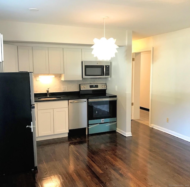 kitchen with white cabinets, dark wood-type flooring, a chandelier, and appliances with stainless steel finishes