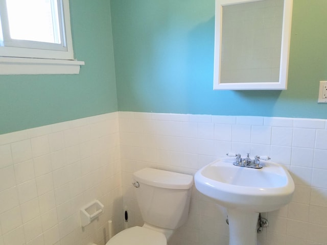 bathroom featuring toilet and tile walls