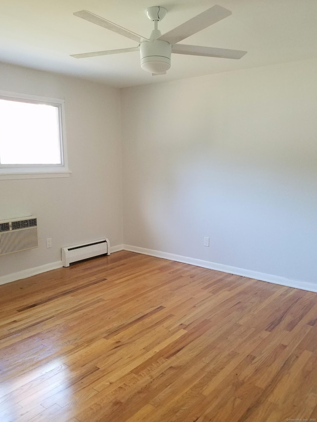 empty room featuring ceiling fan, baseboard heating, light wood-type flooring, and an AC wall unit