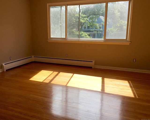 empty room with baseboard heating and hardwood / wood-style flooring