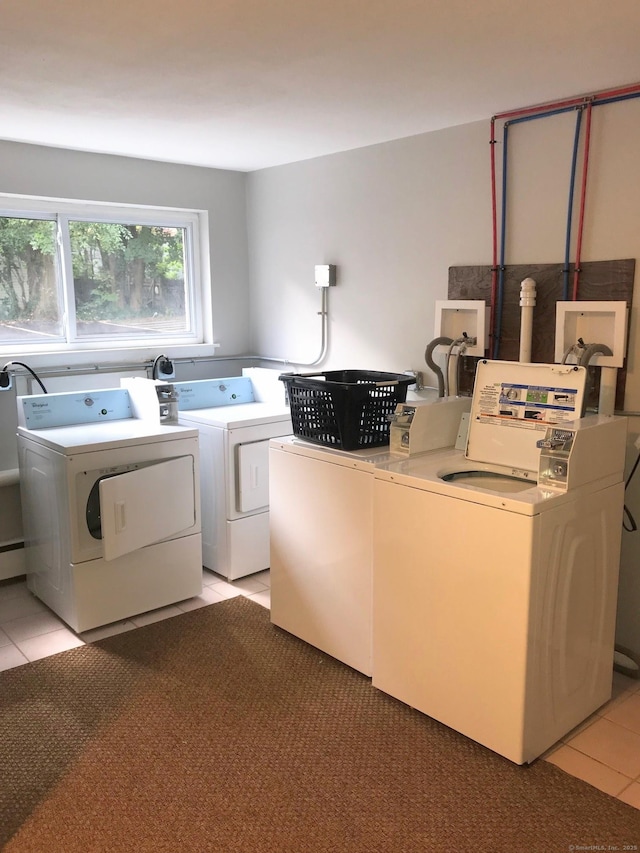 clothes washing area featuring washer and clothes dryer and light tile patterned floors