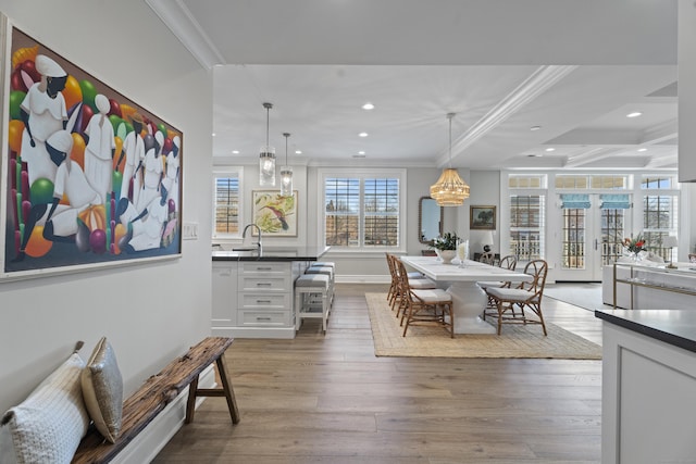 dining space with hardwood / wood-style floors, ornamental molding, sink, and french doors