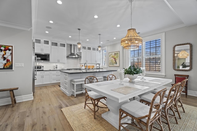 dining room with crown molding, light hardwood / wood-style flooring, a chandelier, and sink