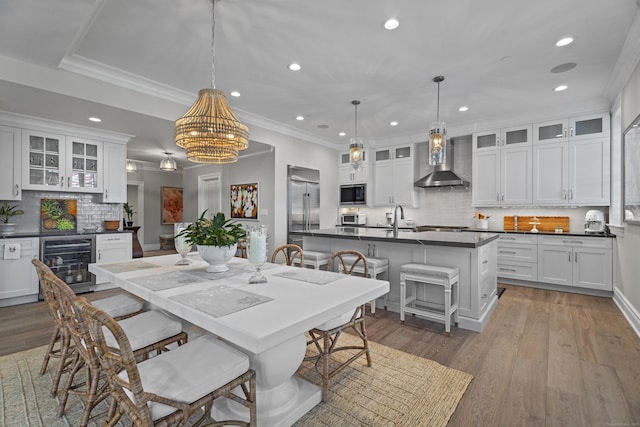 dining room featuring ornamental molding, sink, a notable chandelier, light hardwood / wood-style floors, and wine cooler