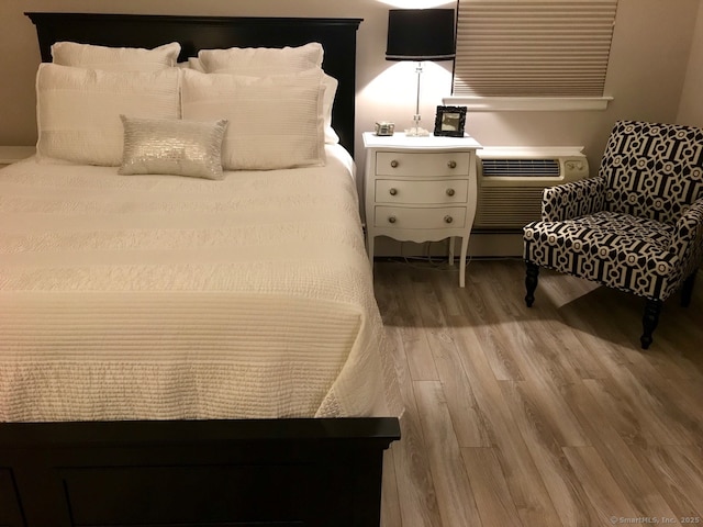 bedroom featuring a wall mounted air conditioner and light hardwood / wood-style floors