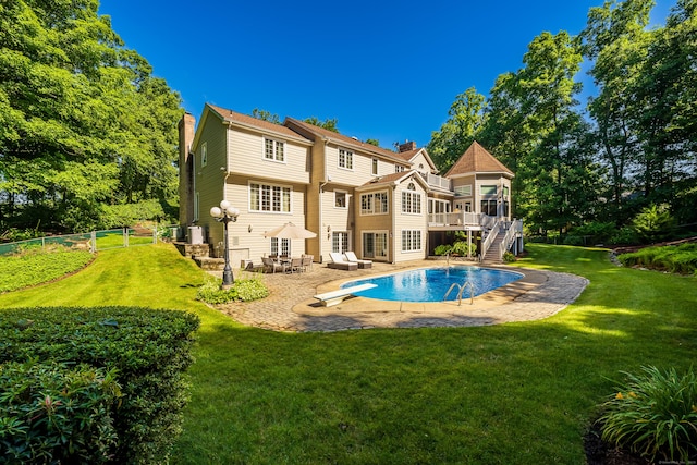 back of property with a lawn, a patio area, and a pool side deck