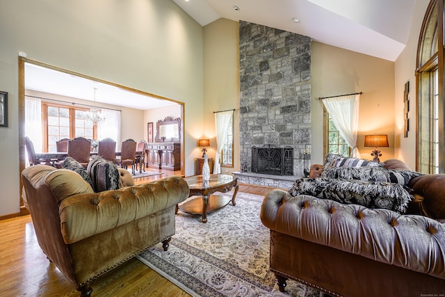 living room with a chandelier, a fireplace, high vaulted ceiling, and light hardwood / wood-style flooring