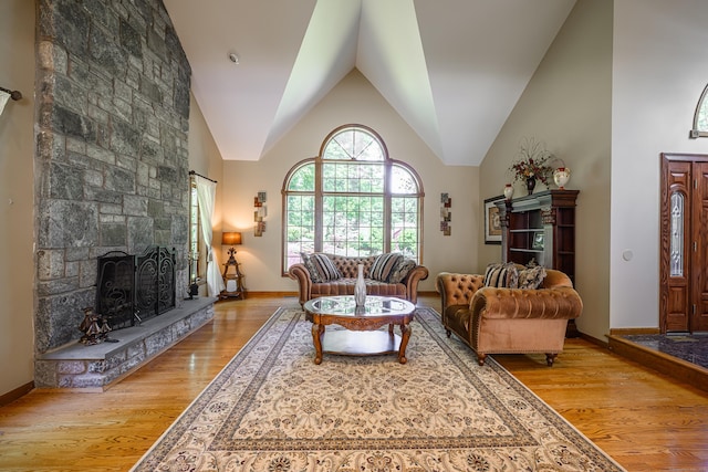 living room featuring lofted ceiling, a fireplace, and light hardwood / wood-style flooring