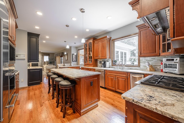 kitchen featuring a kitchen breakfast bar, sink, hanging light fixtures, a kitchen island, and light stone counters