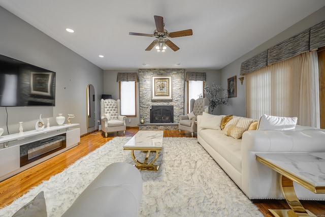 living room featuring a stone fireplace, ceiling fan, and hardwood / wood-style flooring