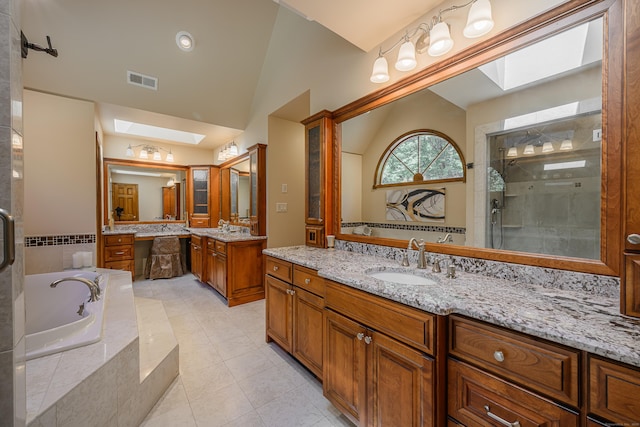 bathroom with tile patterned flooring, shower with separate bathtub, vanity, and lofted ceiling with skylight