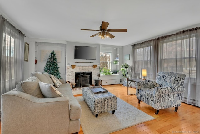 living room with hardwood / wood-style floors, a wood stove, and ceiling fan