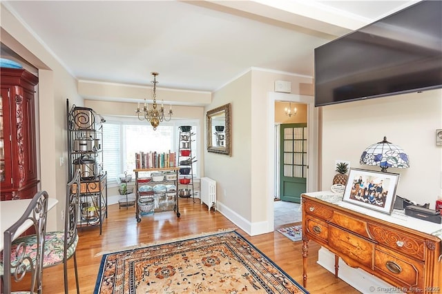 dining space featuring radiator, ornamental molding, a chandelier, and light wood-type flooring