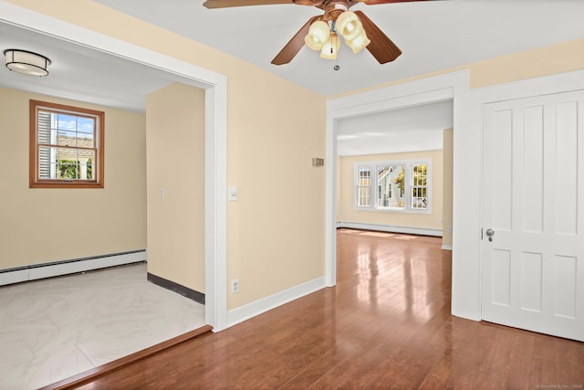 spare room featuring ceiling fan, a healthy amount of sunlight, and a baseboard heating unit