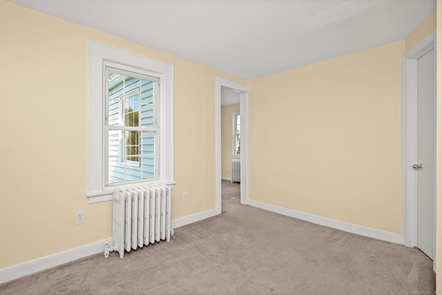 empty room with plenty of natural light, light carpet, and radiator