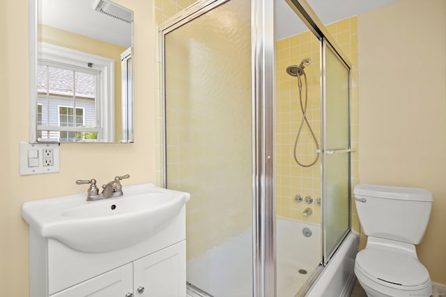 full bathroom featuring combined bath / shower with glass door, vanity, and toilet