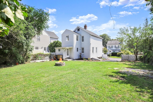 back of property featuring a yard and an outdoor fire pit