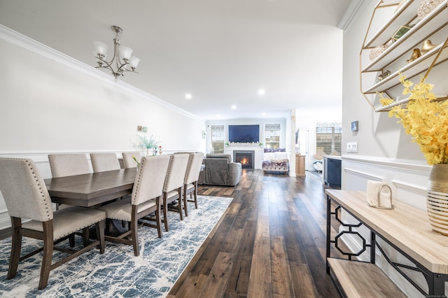 dining room featuring ornamental molding, dark wood-style floors, recessed lighting, a lit fireplace, and an inviting chandelier