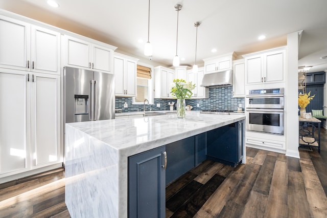 kitchen with dark wood-style flooring, a sink, white cabinets, under cabinet range hood, and appliances with stainless steel finishes