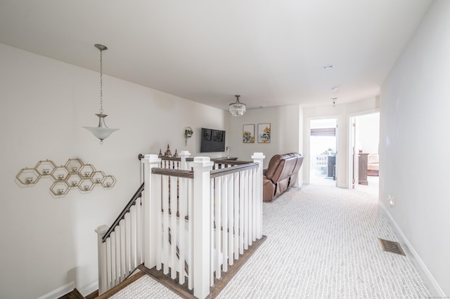 corridor featuring visible vents, an upstairs landing, carpet, and baseboards