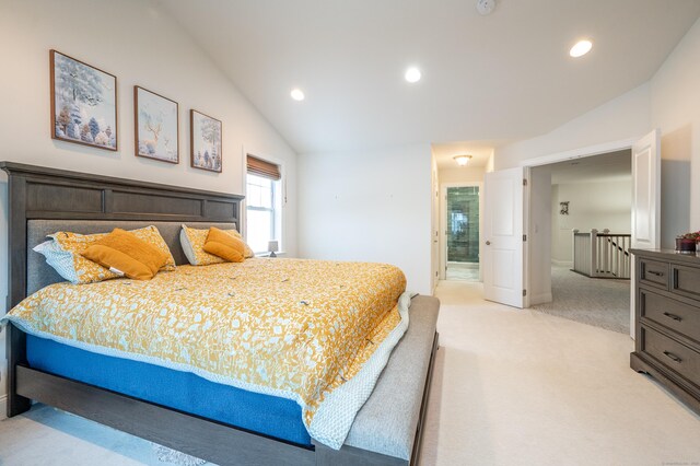 carpeted bedroom with ensuite bath and vaulted ceiling