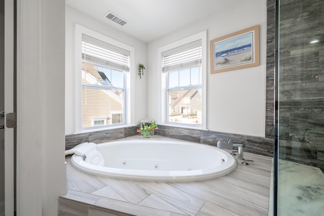 bathroom with visible vents, plenty of natural light, and a jetted tub