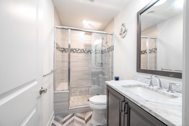 bathroom with vanity, toilet, and a shower with shower door