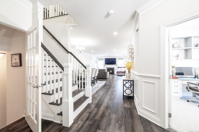 staircase with hardwood / wood-style floors, crown molding, and a chandelier