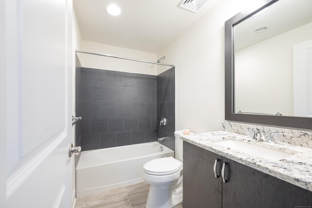 full bathroom featuring tiled shower / bath combo, vanity, and toilet