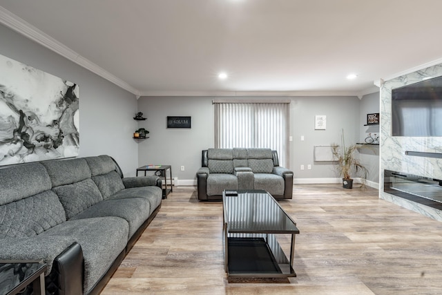 living room featuring crown molding, a premium fireplace, and light hardwood / wood-style floors