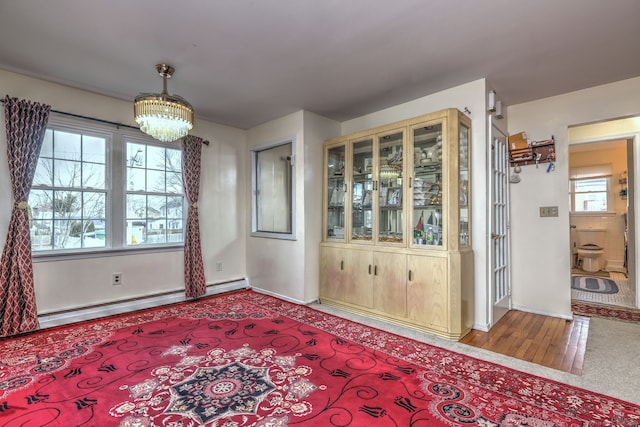 dining room featuring wood-type flooring, a baseboard radiator, and a notable chandelier