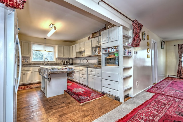 kitchen featuring tasteful backsplash, white cabinetry, a center island, and white refrigerator