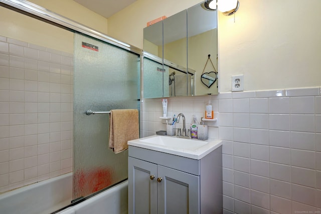 bathroom with tasteful backsplash, shower / bath combination with glass door, vanity, and tile walls