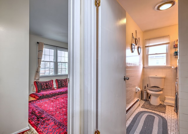 bathroom featuring toilet, tile patterned floors, tile walls, and a baseboard heating unit