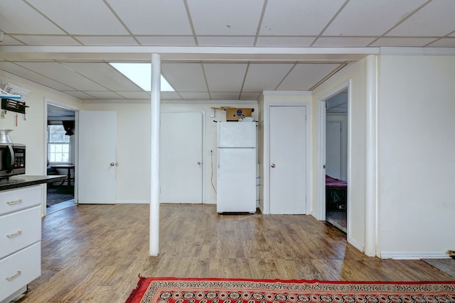 basement featuring white fridge and hardwood / wood-style flooring