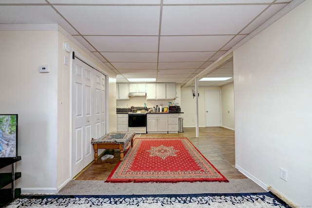 interior space with a paneled ceiling, stove, and hardwood / wood-style flooring