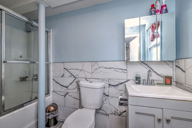 full bathroom with vanity, toilet, shower / bath combination with glass door, and tile walls