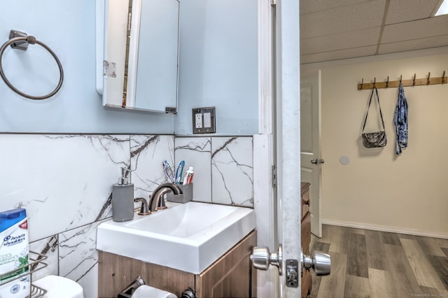 bathroom with hardwood / wood-style floors, a paneled ceiling, toilet, and sink