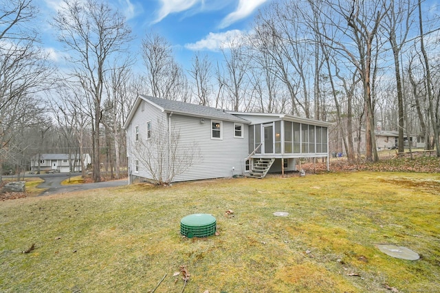 rear view of property with a lawn and a sunroom