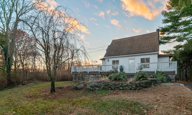 back house at dusk featuring a deck