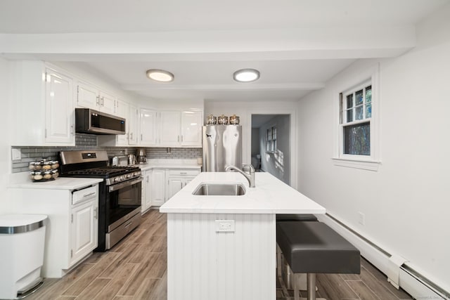 kitchen featuring appliances with stainless steel finishes, an island with sink, white cabinetry, and sink